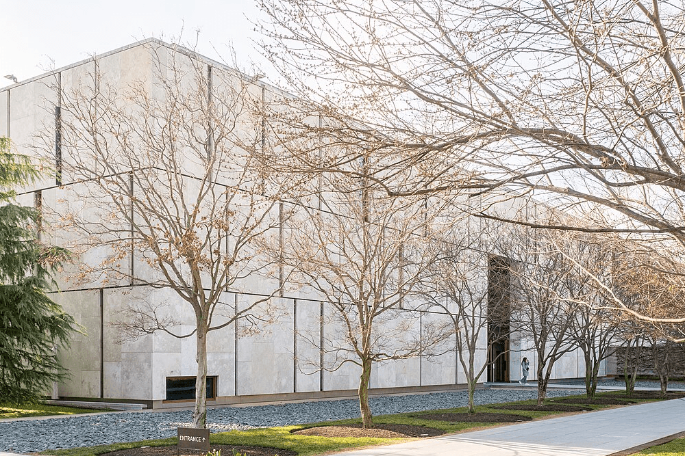 A modern building is framed by bare trees and a clear sky.