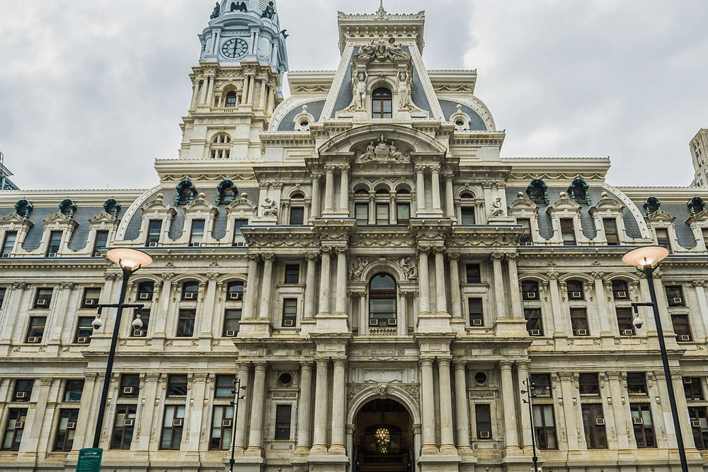 Historic stone building with ornate architecture and a clock tower under a cloudy sky.