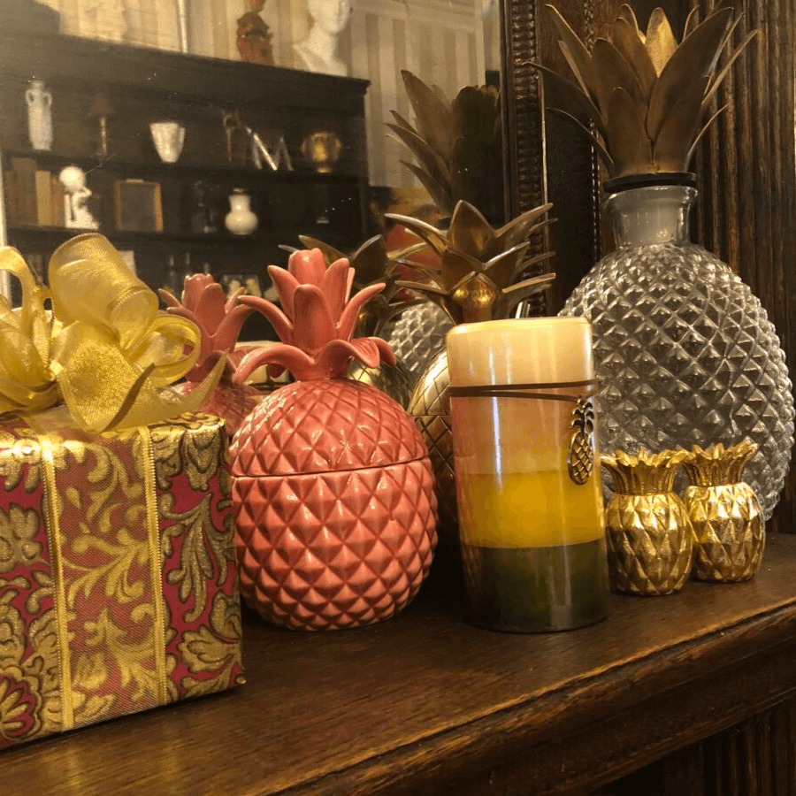Decorative items including pineapples, a gift box, and a candle on a wooden shelf.